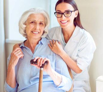 Caregiver smiling with a senior woman holding a cane