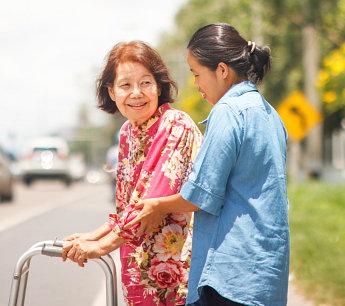 Caregiver walking with a senior woman outdoors