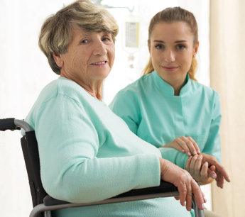 Caregiver with a senior woman in a wheelchair at home