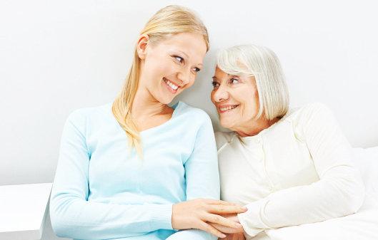 Caregiver and senior woman smiling at each other