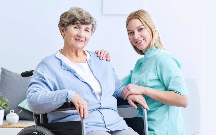 Smiling caregiver with a senior woman in a wheelchair at home