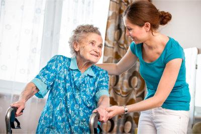 Caregiver helping a senior walk with a walker outdoors