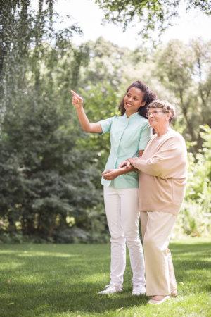 Caregiver walking outdoors with a senior woman